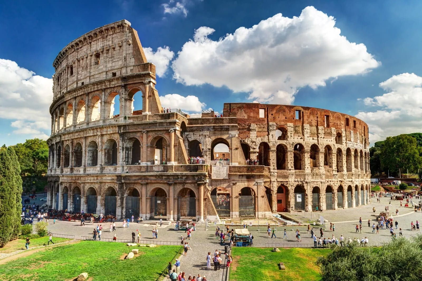 Coliseo Romano bajo cielo azul con nubes en un día soleado